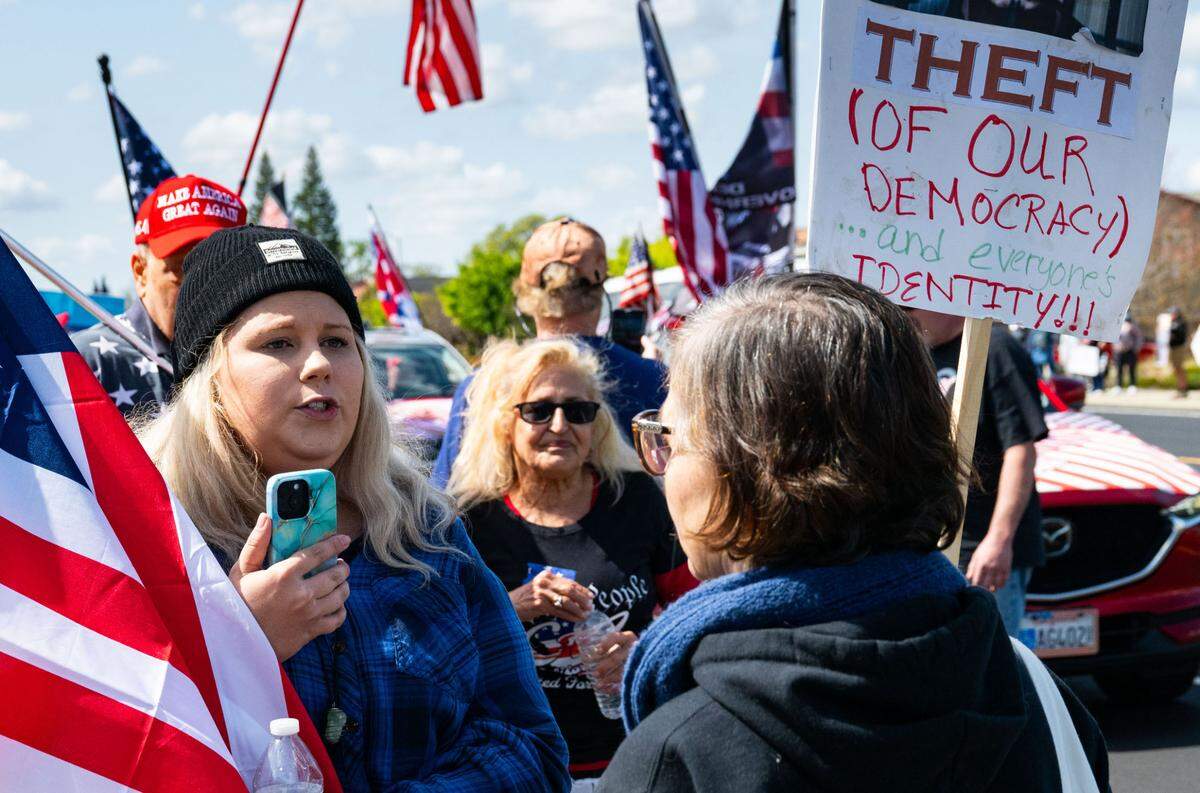 Michaela Swaney, left, carrying a “45” American flag, engages in a civil debate with anti-Tesla demonstrator Christina Rosen down the street from the Rocklin Tesla dealership on Saturday, March 29, 2025.