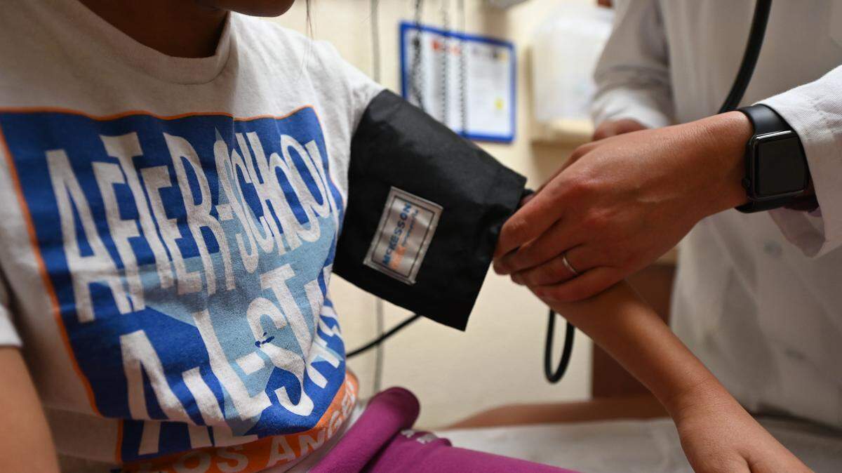 Dr. Ilan Shapiro checks the blood pressure of a young patient at AltaMed Medical in Boyle Heights, east of downtown Los Angeles.