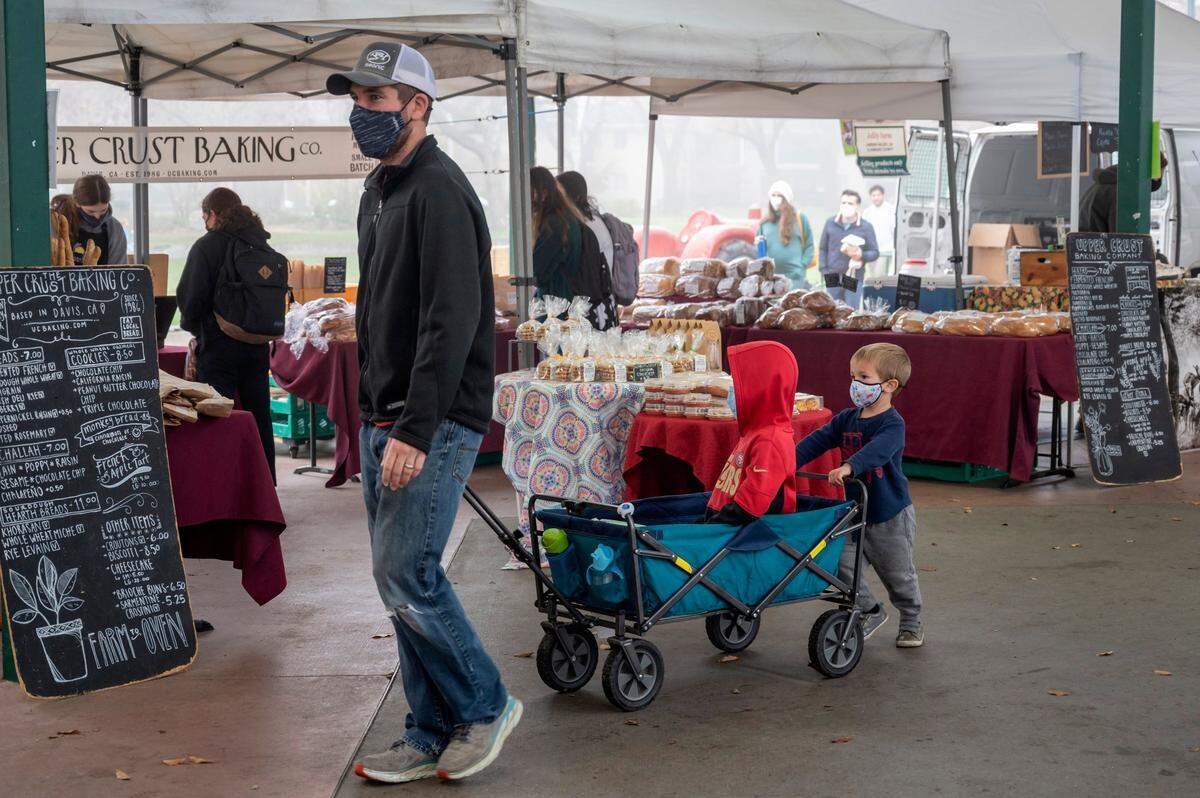 Cape Zern, of Davis with his sons Cooper, 7, and Cruz, 3, ride in a wagon at the Davis Farmers Market at Central Park in Davis on Dec. 4.