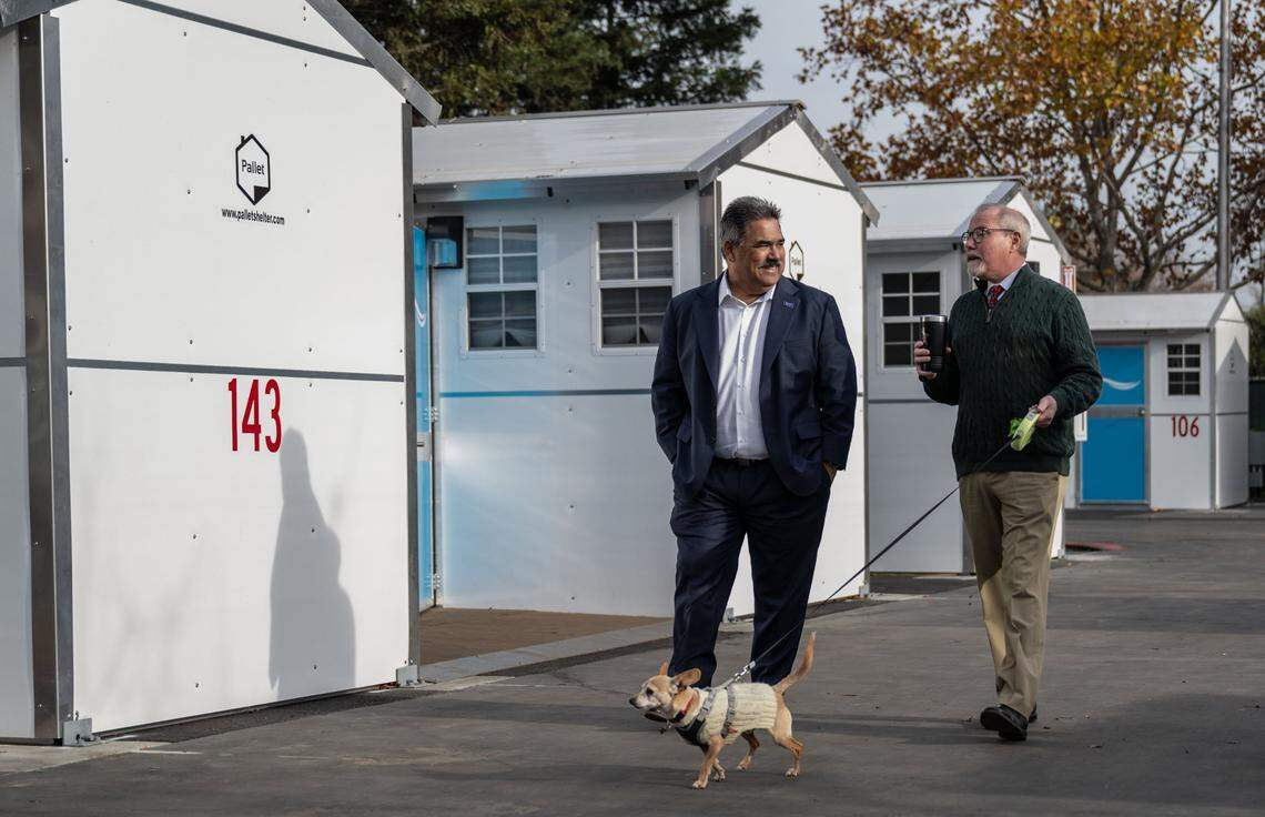 Sacramento County Executive David Villanueva and Supervisor Patrick Kennedy, with his chihuahua Fergus, walk past sleeping cabins at the county’s second Safe Stay homeless shelter on East Parkway in south Sacramento in 2023, a week before the facility’s opening.