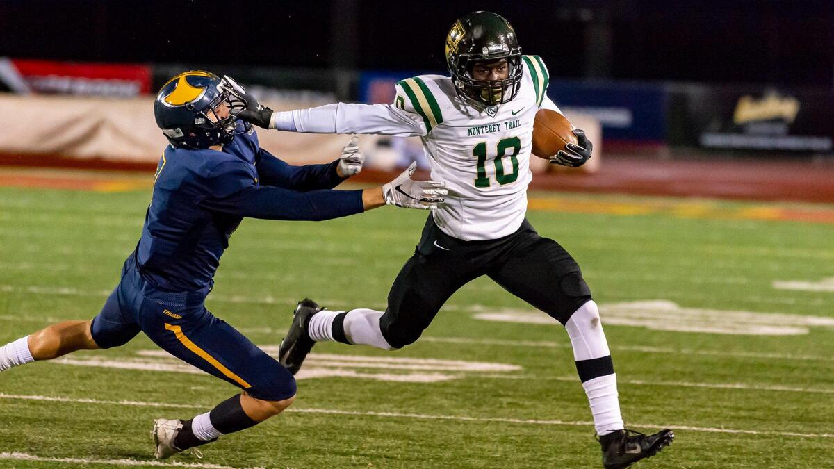 Monterey Trail Mustangs Prophet Brown (10), stiff arms Oak Ridge Trojans Vinni Mini (7), as the Oak Ridge Trojans play the Monterey Trail Mustangs in the Sac-Joaquin Section Division I final Football game at Hughes Stadium in Sacramento, Saturday, November 30, 2019.