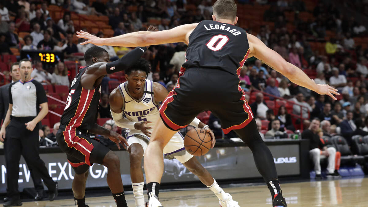 Sacramento Kings guard De’Aaron Fox (5) drives to the basket as Miami Heat guard Kendrick Nunn, left, and forward Meyers Leonard (0) defend during the first half of an NBA basketball game, Monday, Jan. 20, 2020, in Miami. (AP Photo/Lynne Sladky)