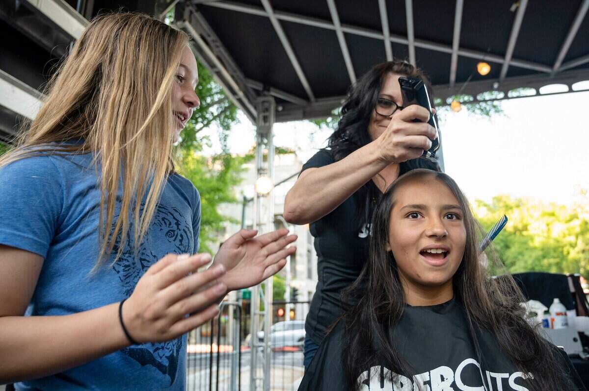 Karyn Sprague, 11, gets her head shaved by Gina Sayers of Lodi Supercuts while her best friend Sofia Little, 11, cheers her on during the St. Baldricks event Monday. Sprague was diagnosed with ganglioneuroblastoma as a one-year-old, and has been cancer free for eight years. She said she wanted to shave her head this year for the first time to support children who are not cancer free.