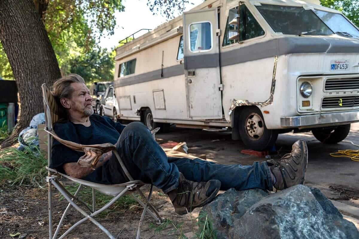 Larry Jankiewicz, 62, rests his legs on a rock in the shade near his motor home across from businesses along Lathrop Way on May 3. He said he was one of the first to arrive after his motor home broke down in the area and he couldn’t get it towed. “Everyday I pray before I go to bed to get me out of this rut,” said Jankiewicz, who struggles to survive on his $900 a month social security check.