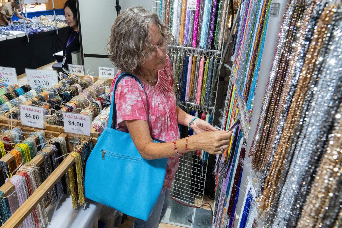 Carol Webster looks through strings of beads during the Gem Faire at the Scottish Rite Masonic Center in Sacramento on Friday, Aug. 2, 2024. Webster said she is looking for a shade of green that matches brat summer.