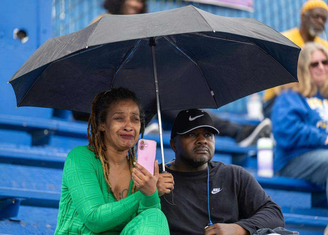 Queen Lee sheds tears as she listens to speakers with her brother Clarence Lee as the Del Paso Heights community celebrated the life of football coach Mike Alberghini at Grant High School on Saturday.