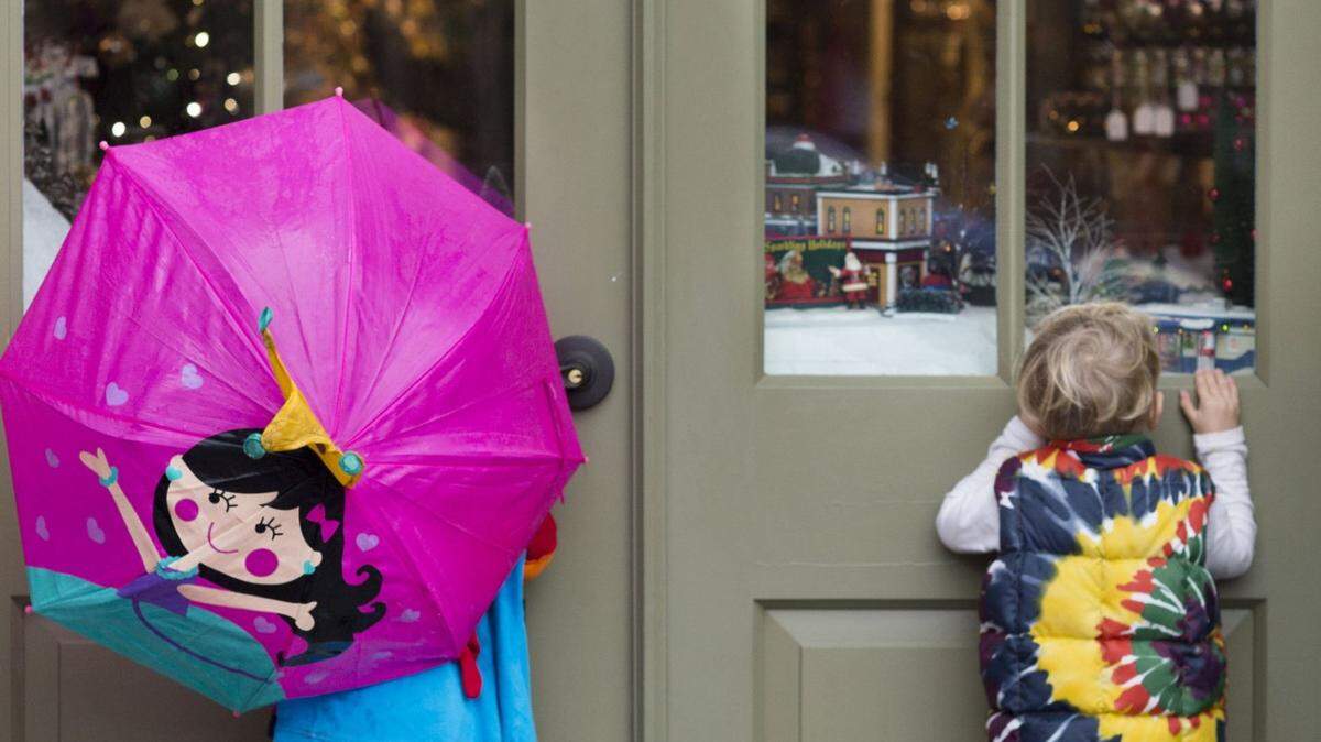 Two youngsters peer into a storefront filled with Christmas decor in Old Sacramento while on a shopping outing with their mom, during a rainy Monday, Dec. 21, 2015.