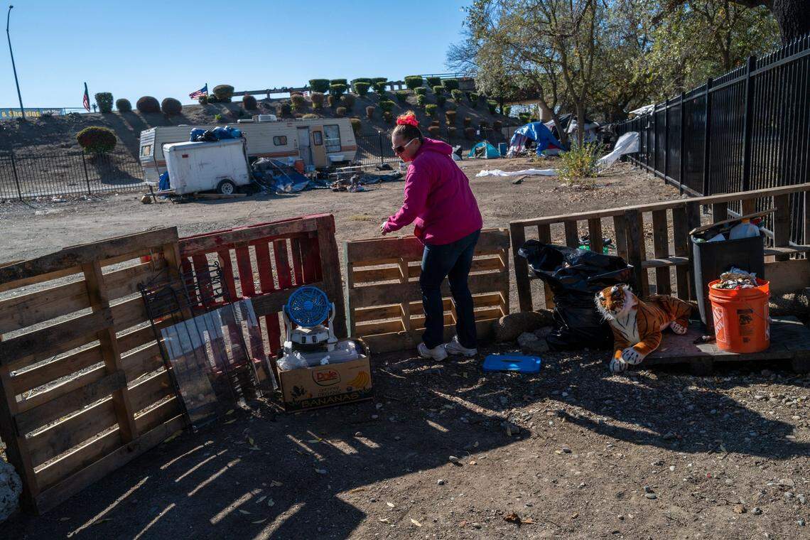 Danyell Mayberry, 42, adjusts a makeshift fence she has for her dog at “Camp Resolution,” at a self governing homeless encampment at Arden Way and Colfax street in North Sacramento on Tuesday. Mayberry questions why the bicyclists are allowed to ride on a path outside the black fenced encampment that the city has called toxic.