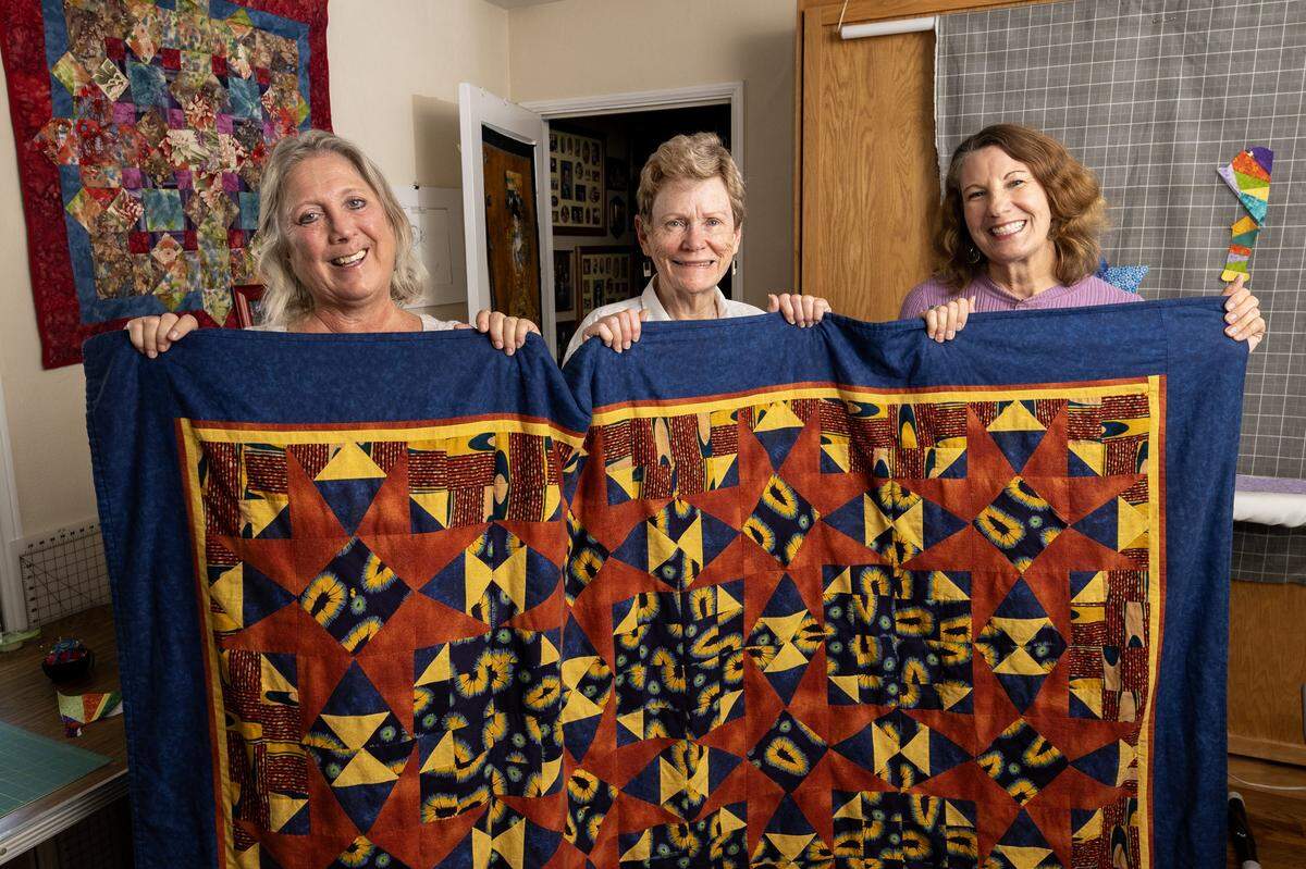 Dion Peart, Colleen Megowan-Romanowicz and Jessa Kay Cruz hold up the first quilt they made together on Nov. 7 in Sacramento. The quilt was made as a graduation gift in 2022.