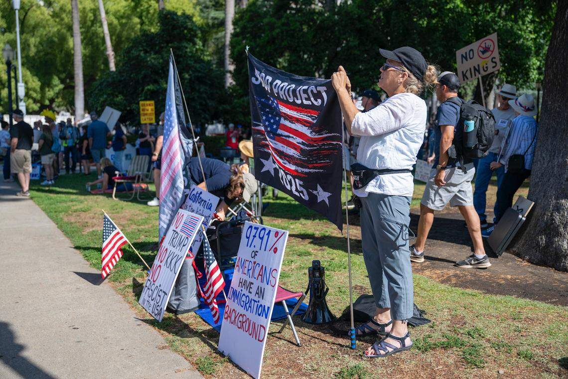 Tanya Homman sets up a “Stop Project 2025” sign at state Capitol mall before the “No Kings” protest against President Donald Trump in Sacramento on Saturday.