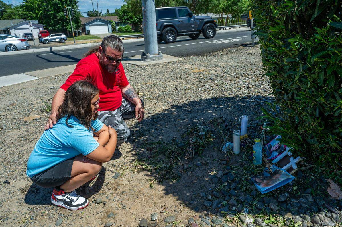 Shawn Jordan’s father Seth Jordan comforts his daughter Lennox, 10, while visiting a memorial for Shawn on Walegra Road in 2024.