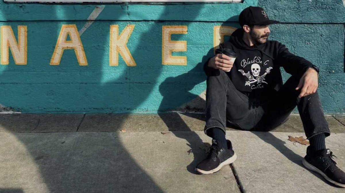 Black Sails Coffee co-owner Sean McCullough enjoys a cup of coffee in front of the former Naked Coffee & Roasting at 3527 Broadway. Black Sails will open in the space this month.