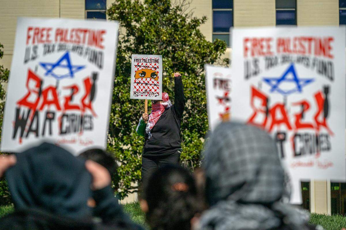 A UC Davis student holds up a fist as she lead chants with other students during a walkout in front of King Hall on Wednesday to protest the suspension of the Law School’s student leadership organization, known as the LSA, after it resolved to boycott Israel for its actions in Gaza. Students wore masks to protect their identity in fear of retaliation for taking a stand.