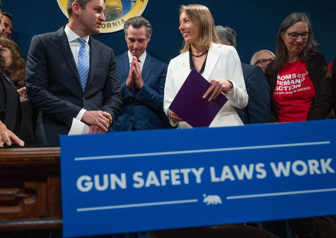 Gov. Gavin Newsom presses his hands together on Tuesday after signing three gun control bills, including ones authored by Assemblyman Jesse Gabriel, D-Woodland Hills, left, and state Sen. Catherine Blakespear, D-Encinitas, right.