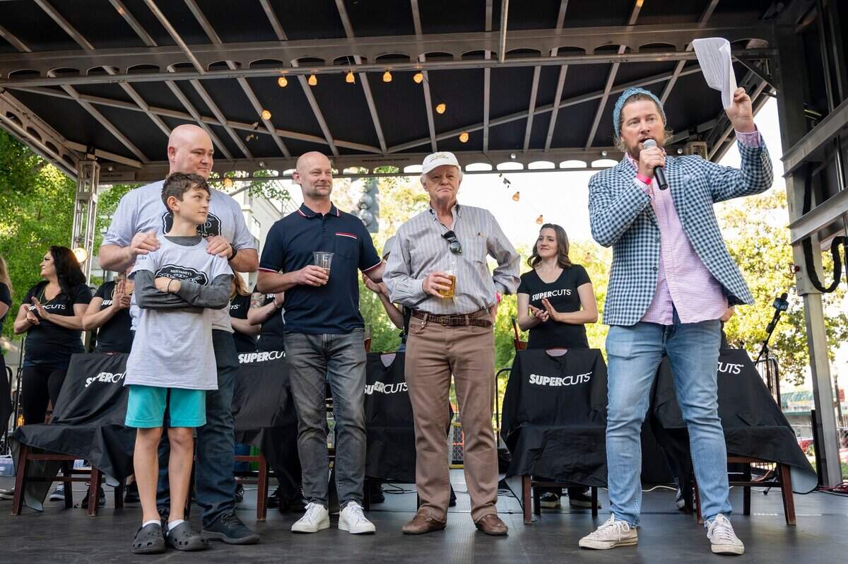 Henry de Vere White, left, with his son Alex, 12, his brother Simon, center, and their father Ralph get introduced by Patrick Harbinson during the St. Baldricks event on Monday.