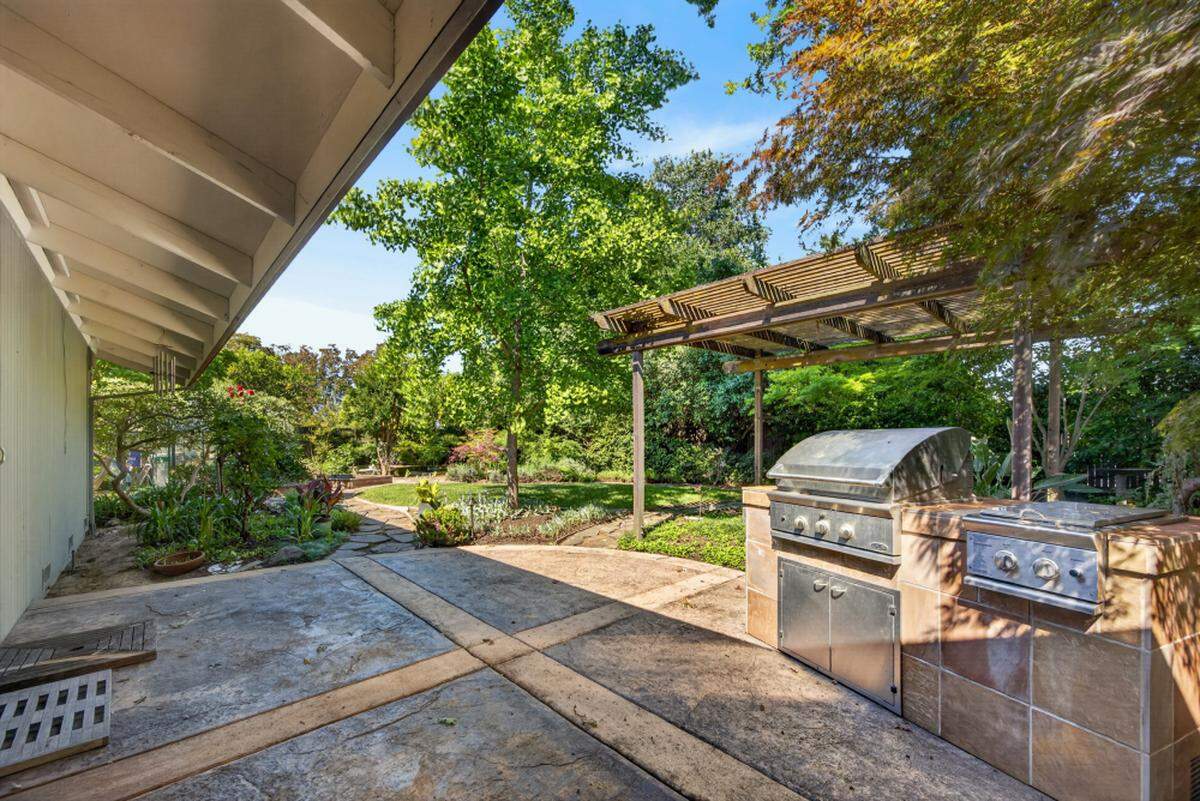 A Japanese-inspired landscape with mature trees, water features, raised beds and a greenhouse turns the backyard into a retreat. There’s also an outside grilling kitchen.