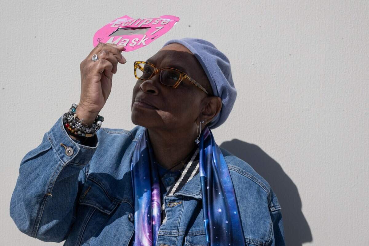 Beatrice Hogg of West Sacramento looks at the solar eclipse at the Museum of Science and Curiosity in Sacramento on Monday, April 8, 2024, with a viewer she made for the 2017 eclipse. She is wearing science-inspired clothing and said she has been interested in astronomy since she was a child.