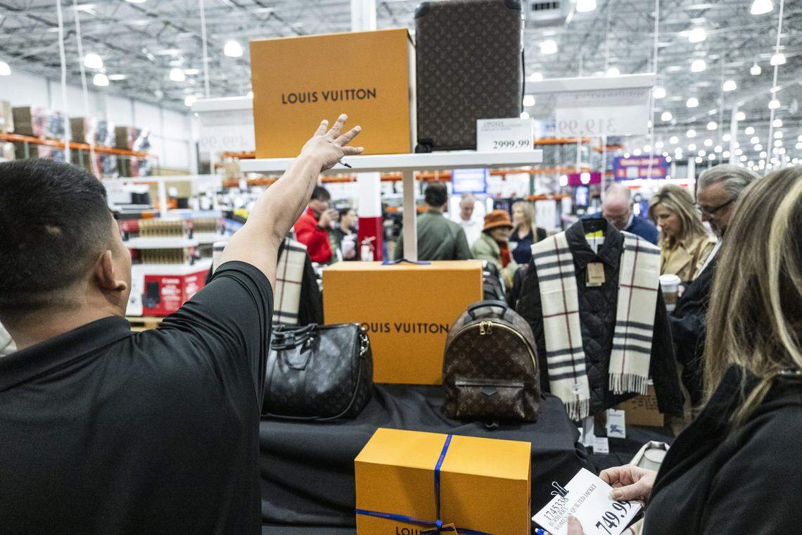 A Costco employee points to the available Louis Vuitton products during the grand opening on Baseline Road in Roseville on Friday. The products were among the high-ticket items available for purchase and sold quickly.