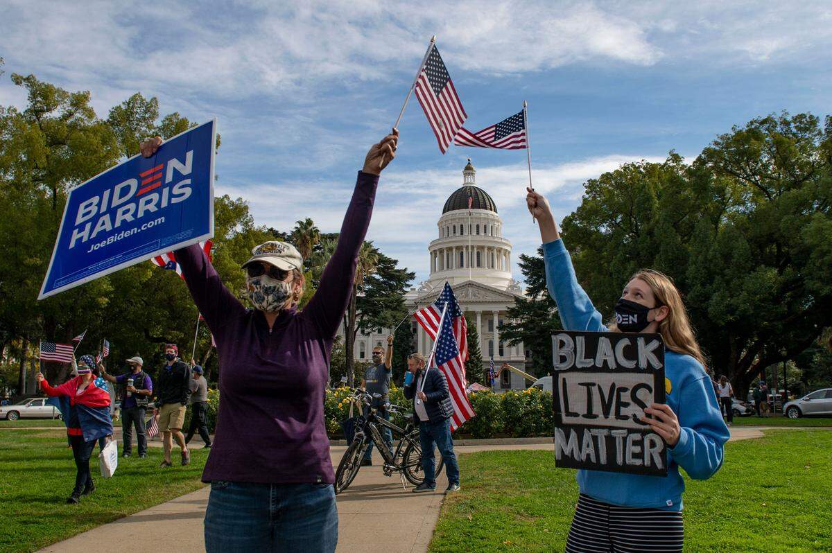 Sandy Hampton of Sacramento and first time voter Mira Saab, 18, celebrate at the capitol after the announcement Saturday, Nov. 7, 2020, that Joe Biden will become the 46th president of the United States.