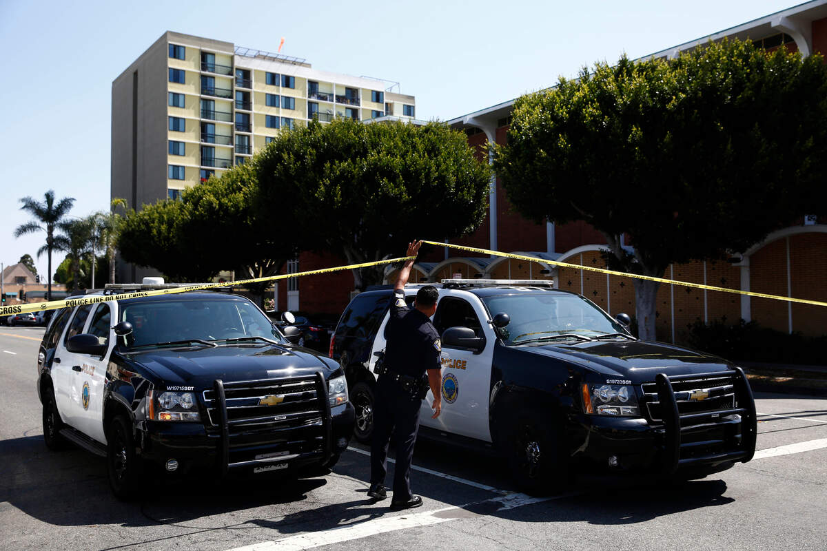 Long Beach, California, police keep a street closed off near a retirement home, seen in background on Monday, June 25, 2018. A resident of a retirement home in Southern California opened fire on firefighters responding to a report of an explosion in the building, killing at least one and wounding others, officials said.