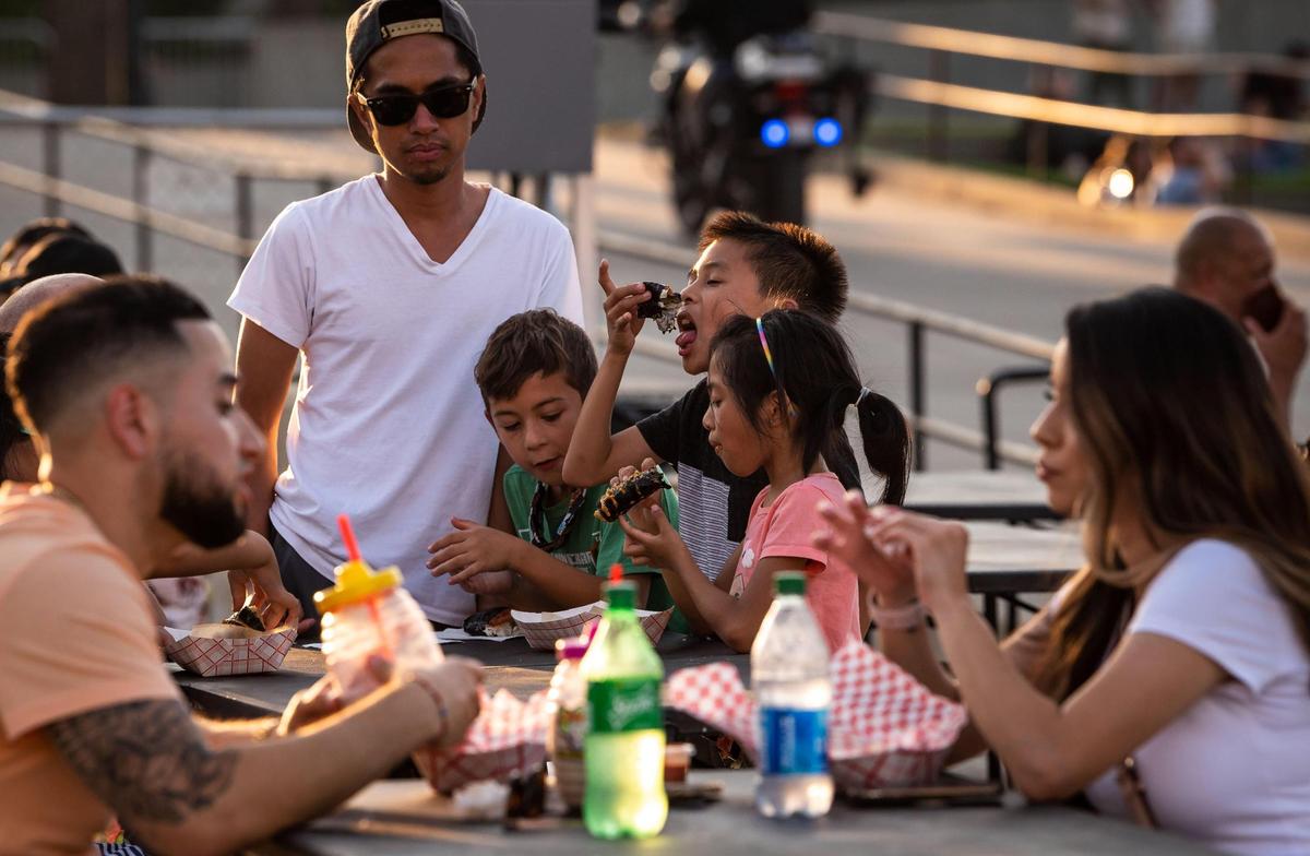 Jace Santos, 8, center, eats Spam musubi along with his sister Arya Santos, 7, right, and neighbor Dominic Pudwill, 7, all of Roseville, during the second of four nights at FoodieLand Night Market for an Asian inspired pop-up festival at Cal Expo on Saturday, Sept. 4, 2021, in Sacramento.