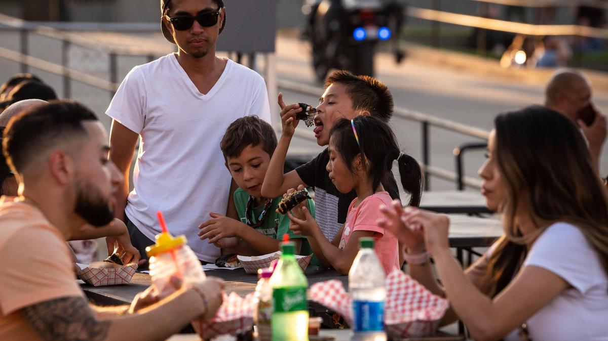 Jace Santos, 8, center, eats Spam musubi along with his sister Arya Santos, 7, right, and neighbor Dominic Pudwill, 7, all of Roseville, during the second of four nights at FoodieLand Night Market for an Asian inspired pop-up festival at Cal Expo on Saturday, Sept. 4, 2021, in Sacramento.