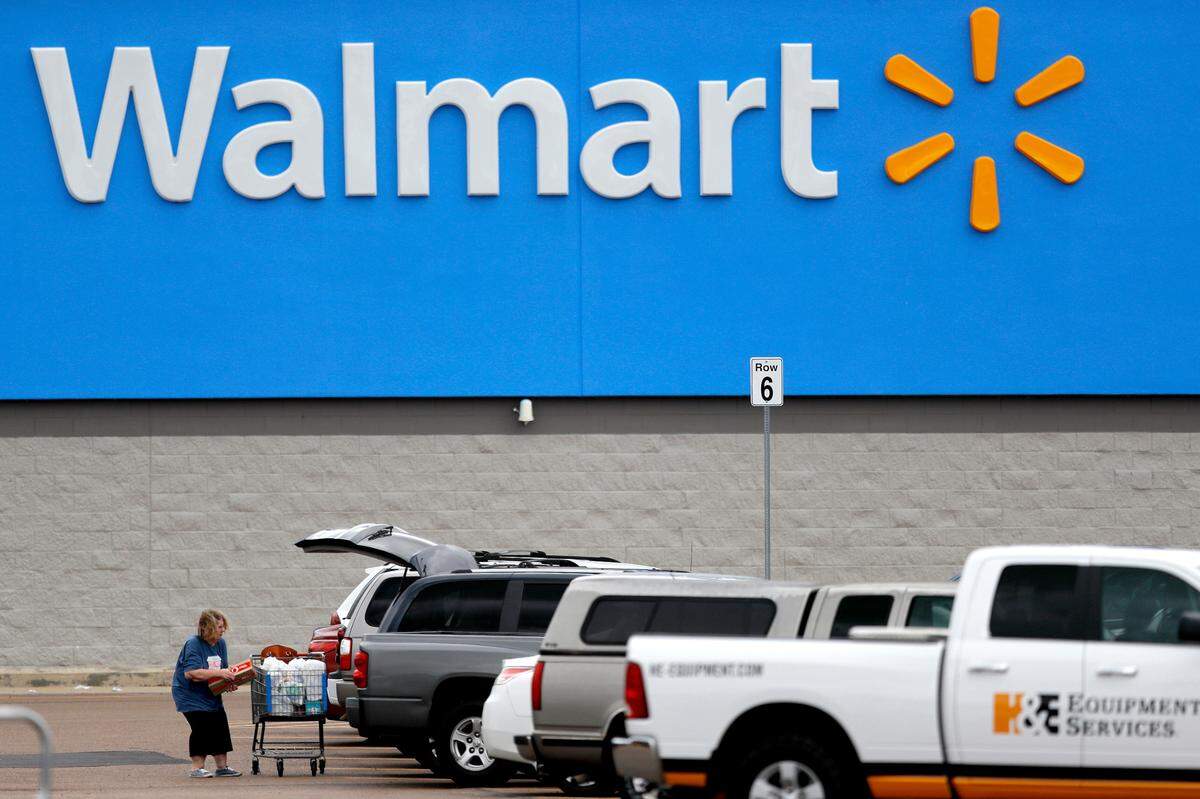 FILE - In this March 31, 2020 file photo, a woman pulls groceries from a cart to her vehicle outside of a Walmart store in Pearl, Miss. Walmart became a lifeline to millions of people as the coronavirus spread, and its profit and sales surged during the first quarter, topping almost all expectations. (AP Photo/Julio Cortez, File)