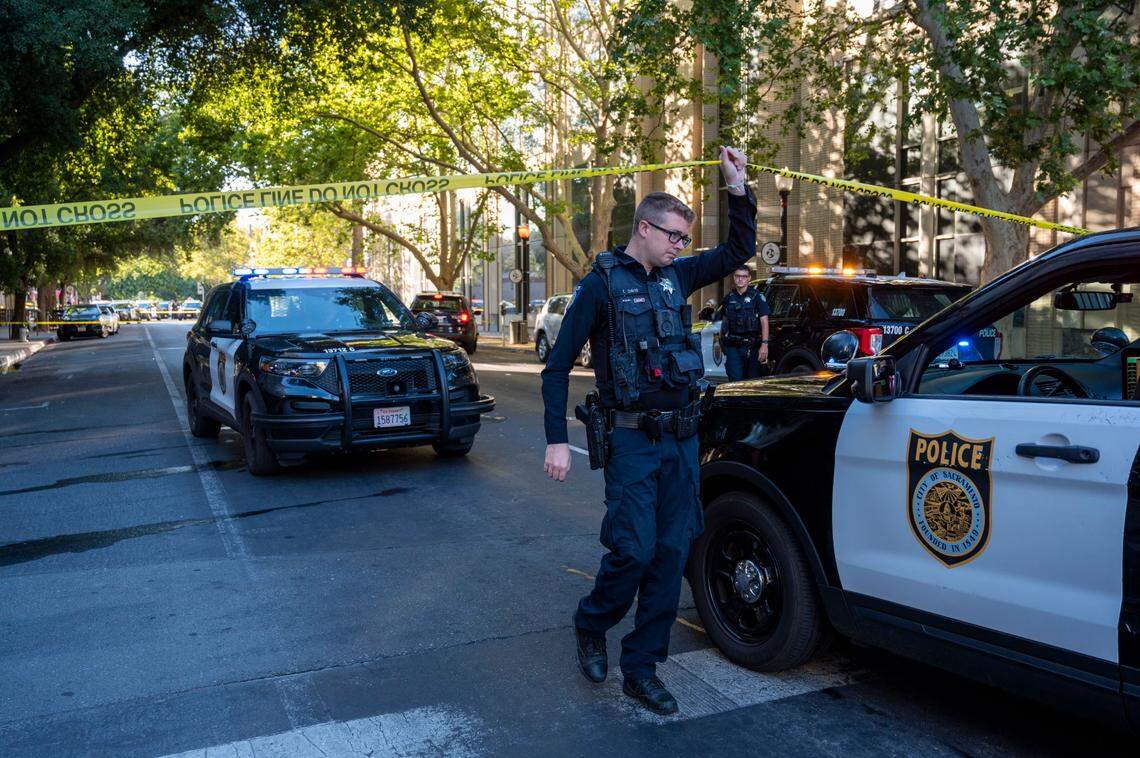 A Sacramento Police officer allows vehicles through the police tape at 15th and L streets in Sacramento on Monday as they investigate the scene of a shooting outside the Mix nightclub at 16th and L streets in downtown Sacramento.