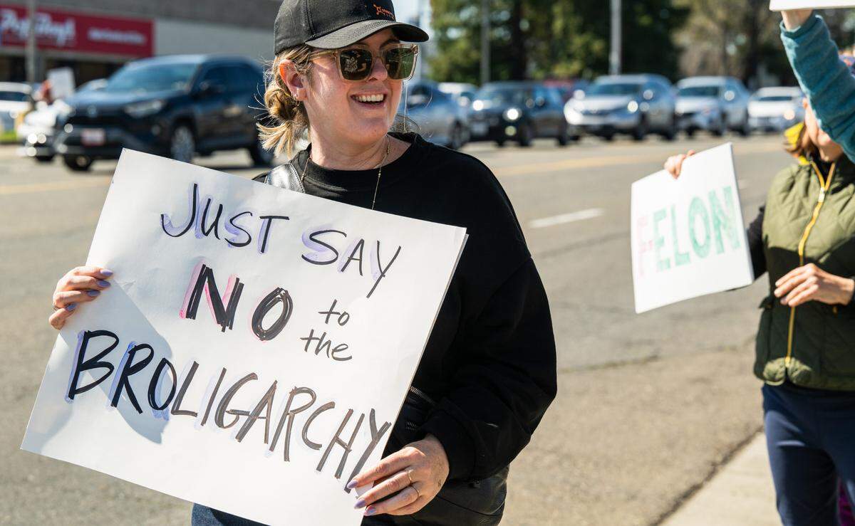 “Just say no to the broligarchy” reads a sign at a rally against Elon Musk at a Tesla dealership on Arden Way near Sacramento on Saturday, March 8, 2025. More than 100 people lined both sides of street to protest the role of the tech billionaire and Tesla CEO in the Trump administration.