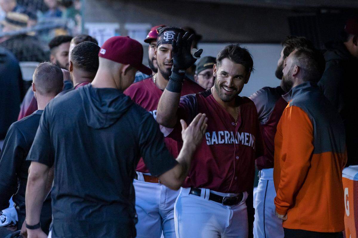 Sacramento River Cats infielder David Villar (32) is congratulated in the dugout after hitting a home run in the bottom of the second inning at the home opener against the Sugar Land Space Cowboys on Tuesday, April 5, 2022, at Sutter Health Park in West Sacramento. Villar had four at-bats, two hits and four RBIs. The River Cats won 7-6.