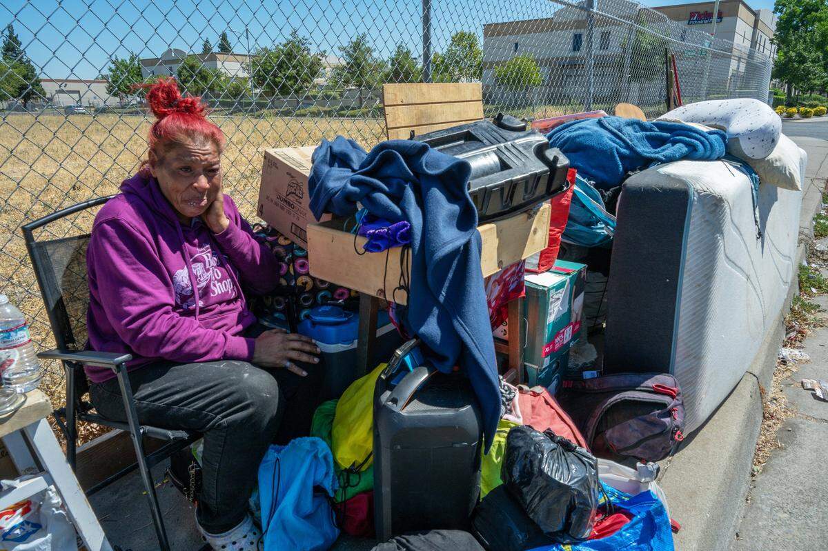 Miss Sanchez, 54, sits with her belongings on Harris Avenue in North Sacramento in July. She said her trailer was taken four days ago in triple-digit heat. “It’s not right what they are doing and Gov. Newsom you should be ashamed of yourself because I really thought you were on our side,” said Sanchez, wiping away her tears, of the governor’s order for state agencies to begin sweeping homeless encampments on public property.