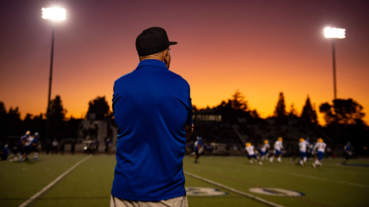As the sun sets, Grant High School head coach Mike Alberghini stands on the sideline as his team plays at Davis High School, Friday Aug 23, 2019.