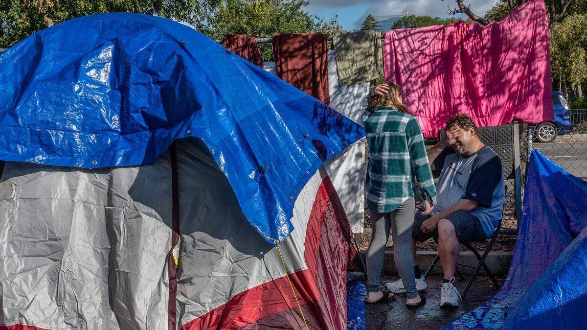 Jeff McDowell, 50, and his wife Ashleigh McDowell, 29, take a break from hanging blankets and clothing to dry on Monday, Oct. 25, 2021, at the homeless Safe Ground on near 8th and W streets in Sacramento. They said their tent collapsed during Sunday’s storm and they had to buy another one.