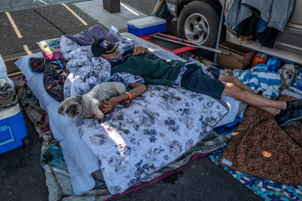 Derek Jones, an evacuee from Foresthill, rests on a mattress alongside his dogs Colonel Nelson, 15, and Rosco P. Coltran, 20, in Parking Lot B at Sierra College in Rocklin on Thursday. “I didn’t grab anything for myself. I grabbed my puppies and anything they needed,” said Jones. He said he prefers to stay with his dogs in the parking lot instead of inside the Red Cross because he doesn’t want to be separated from them.