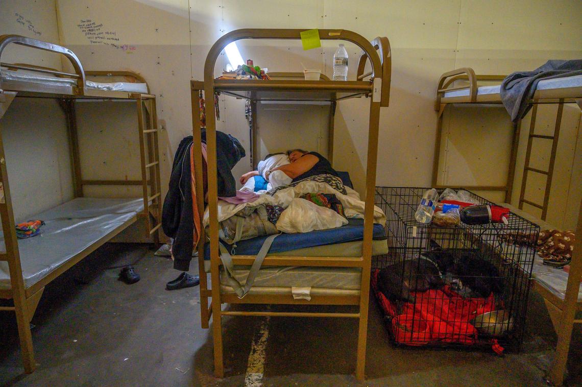 Debbie Scheible, 63, says she has a hard time walking and standing on her feet before laying down to take a nap inside the Railroad Drive shelter near her dog Patrice, sleeping in the cage at right, on Friday, April 26, 2019 in Sacramento. “I need my dog, she is all I got,” said Scheible.