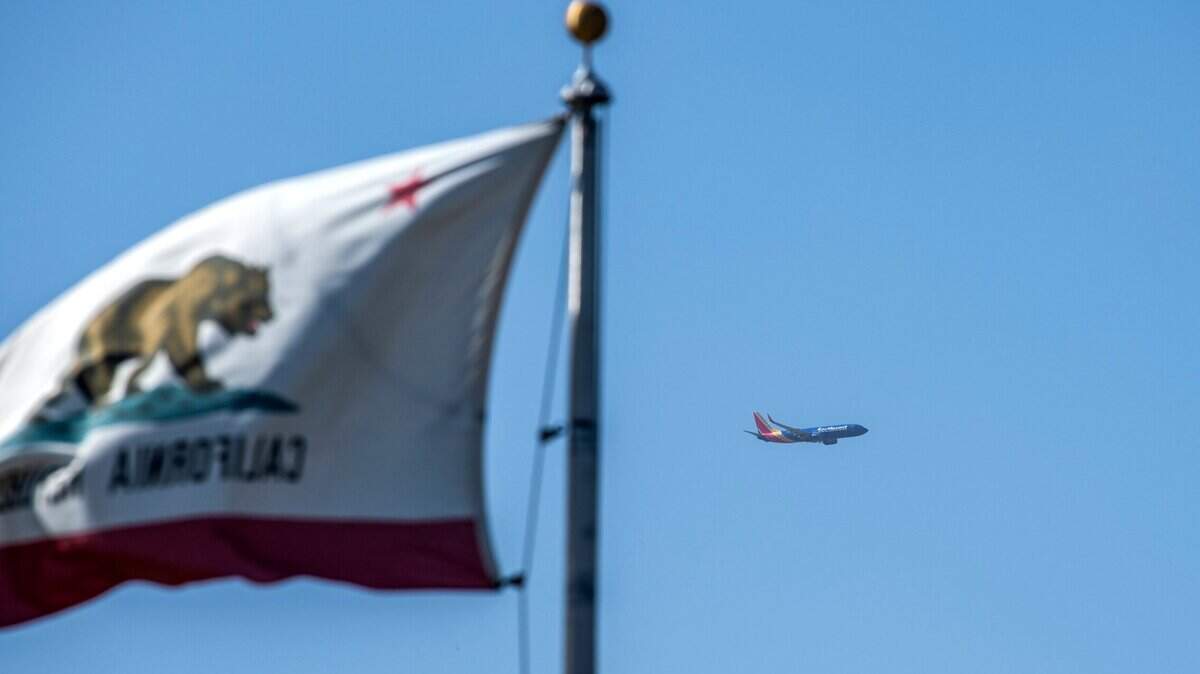 A Southwest plane leaves the Sacramento International Airport on Monday, Oct. 11, 2021 as high winds blow a California state flag in West Sacramento.