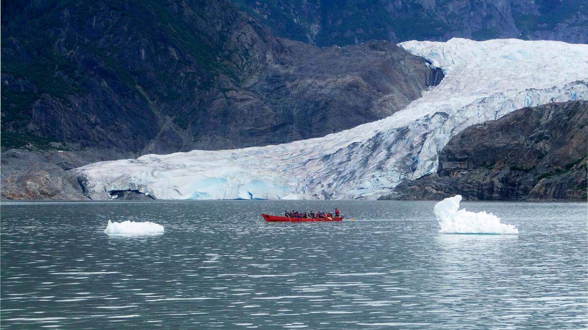 Kayakers paddle on Mendenhall Lake, with Mendenhall Glacier in the background and icebergs in the foreground, near Juneau, Alaska in 2017.