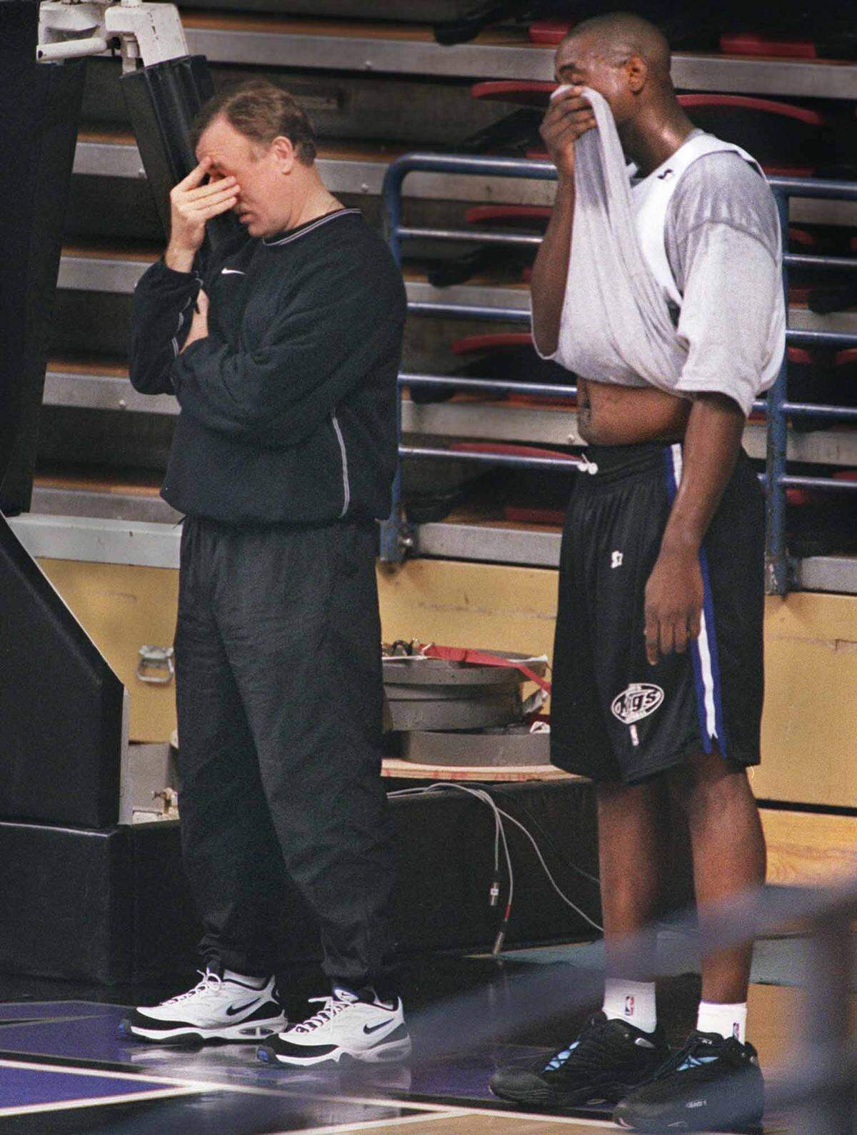 Sacramento Kings head coach Rick Adelman rubs his eyes as Chris Webber wipes his face off during his first practice with the team on Jan. 22, 1999.