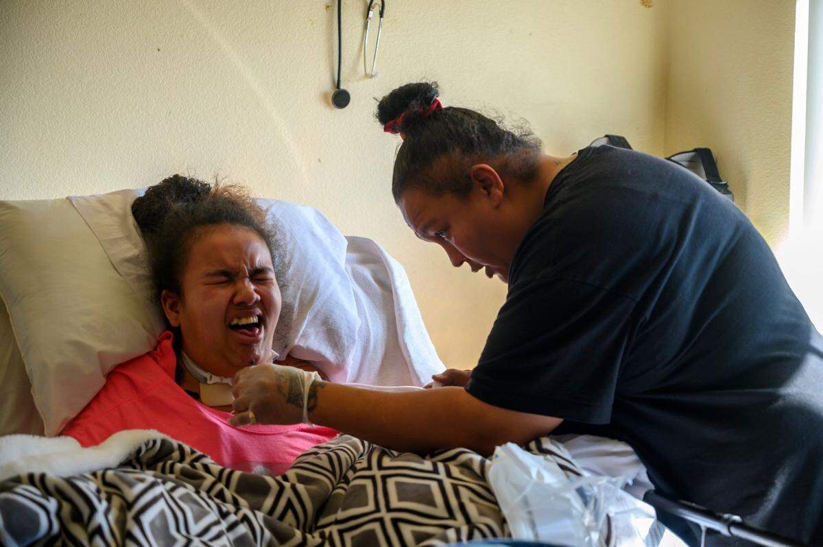 Felicia Clark suctions the opening in her daughter Felicia Brent-Valesquez’s trachea so she can breathe at their home in Sacramento in February. “I have no training, I’m not a nurse but I’m doing everything for her,” said Clark. Her daughter was taken away by CPS in 2016 but was returned home after going AWOL from the county’s foster care placement facility on the Auburn Boulevard campus. She later got into a car accident that left her paralyzed from the neck down. In June, she suffered a stroke and died.
