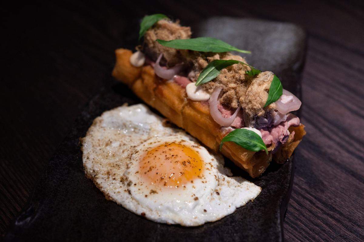 The country pork pate toast, made with pickled shallots, maggi aioli, rau ram, chicken liver mousse and served with a sunny-side up egg, is the most popular item on the menu at Chu Mai.