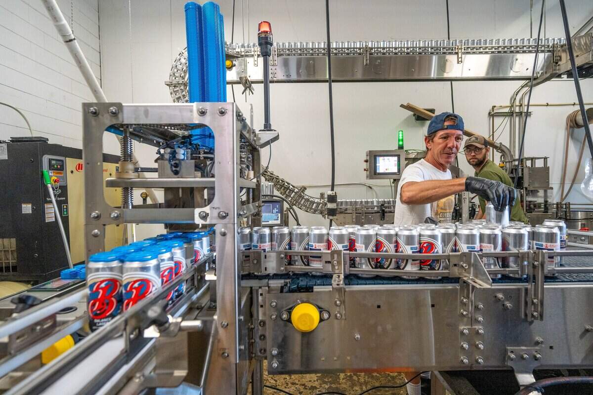 Co-owners Bruce MacPhee, left, and Ian Marriott, right, of Balance Beerworks, a new brewery that is set to open at the old Device Brewing Co. space in Sacramento, checks cans of rice lager on the assembly line on Monday, June 8, 2026. They are part of a five-member ownership group.