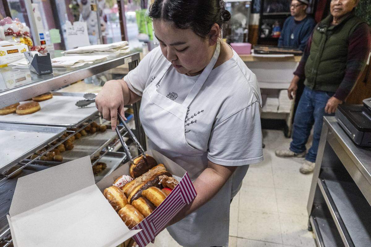 Melody Mua packages doughnuts at Broadway Donuts on Friday, the first day the shop was under new ownership.