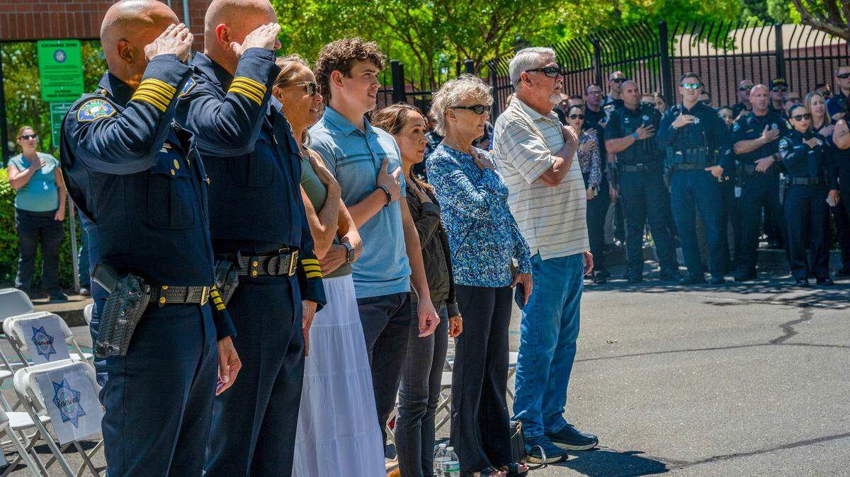 Chief Bobby Davis and Assistant Chief Brian Schopf of the Elk Grove Police Department salute during the Pledge of Allegiance at a dedication ceremony honoring fallen Officer Ty Lenehan on Wednesday, May 13, 2026, in Elk Grove. The department honored Lenehan, killed in the line of duty in 2022, by renaming its campus the Officer Ty Lenehan Public Safety Center and unveiling a memorial plaque recognizing his service and legacy.
