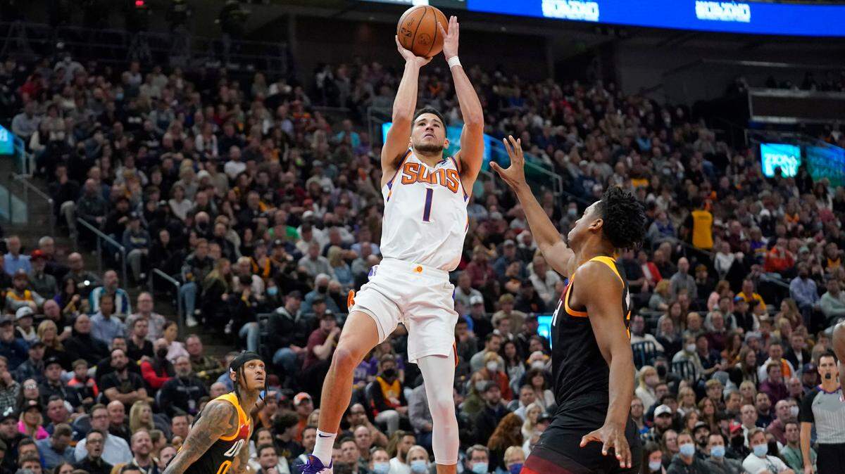 Phoenix Suns guard Devin Booker (1) shoots as Utah Jazz center Hassan Whiteside, right, defends in the second half during an NBA basketball game Wednesday, Jan. 26, 2022, in Salt Lake City. (AP Photo/Rick Bowmer)