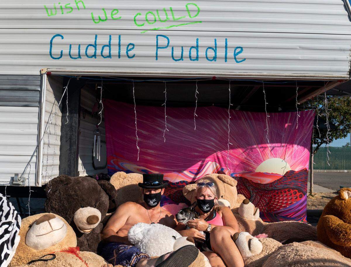 James Leis, left, and his wife, Lisa, sit in the Cuddle Puddle with their dog Bugsy at Summer Spark, a nighttime drive-thru festival inspired by Burning Man, at the Mine Shaft Center in Rancho Cordova on Friday, July 24, 2020. They usually have a camp at Burning Man called Roasted Breaux and Coffee Heaux, which includes a cuddle puddle. They are the only ones using it at the drive-thru due of coronavirus concerns.