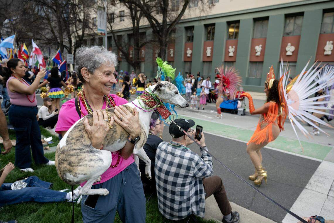 Julie Hersch cradles her dog Pliny as they watch performers on Capitol Mall during the City of Trees Parade on Saturday, Feb. 28, 2026.