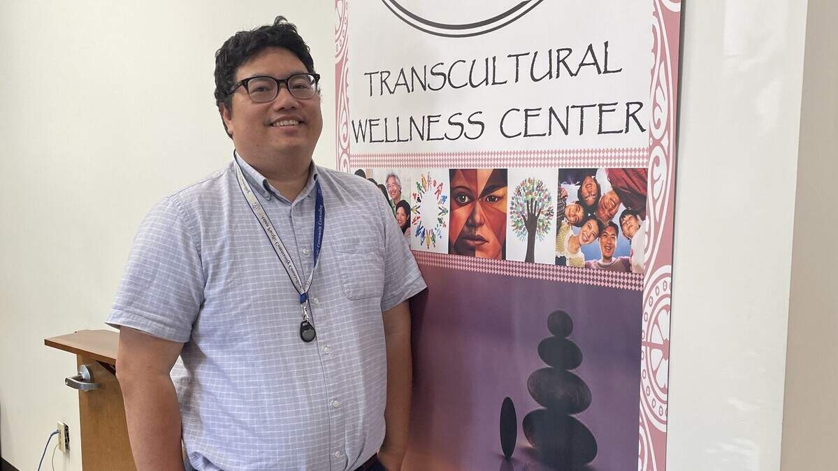 Quang Tran, a clinician for Asian Pacific Community Counseling, stands in front of the center’s signage on June 5, 2024. Tran has worked with Asian Pacific Community Counseling for four years, where he works in the program’s suicide prevention program.