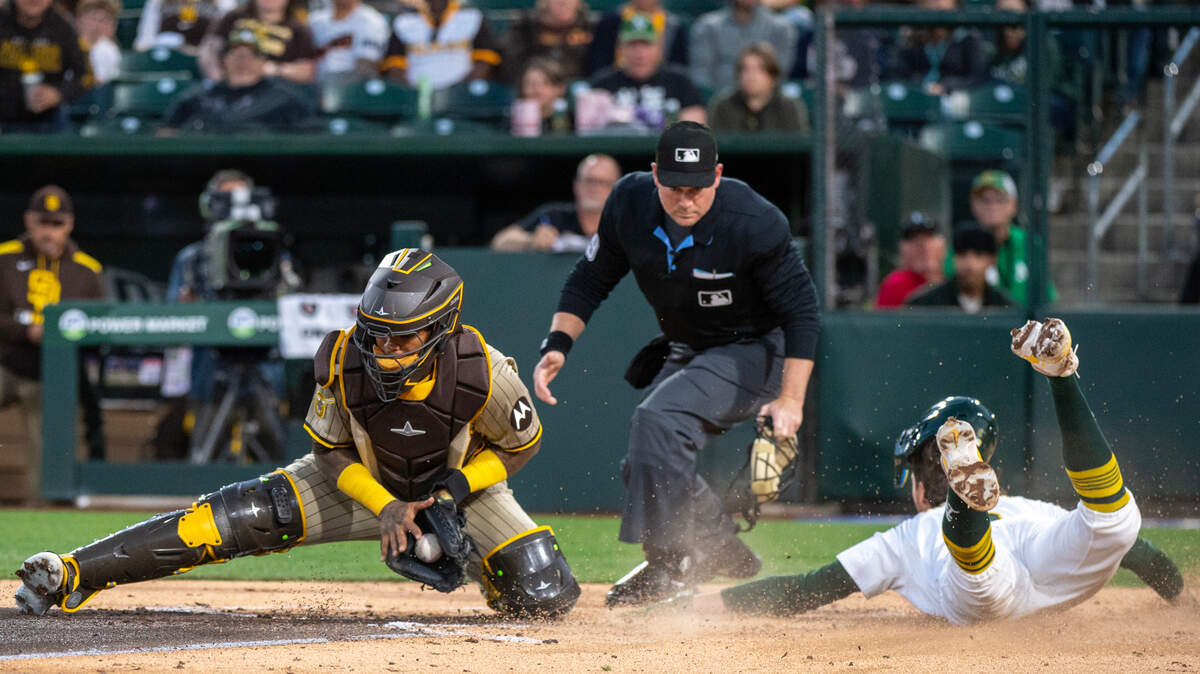  Athletics baserunner Jacob Wilson (5) slides past San Diego Padres catcher Martín Maldonado (15) scoring on a Gio Urshela hit in the bottom of the first inning on Tuesday at Sutter Health Park in West Sacramento. The A's won their first game 