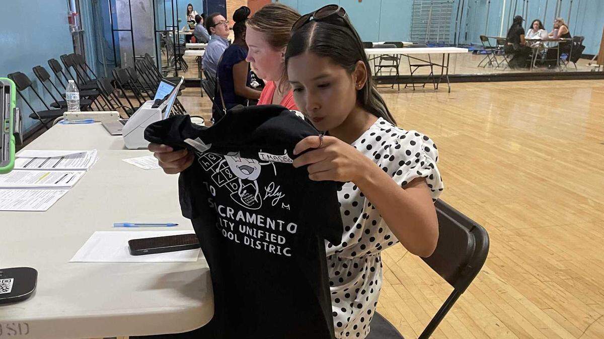 Alejandra Rodriguez admires the T-shirt gifted to her upon learning that she has been hired as a special education instructional aide for Sacramento City Unified School District on Monday.