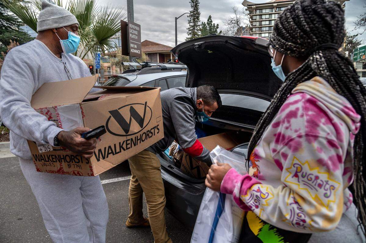 Quinton Watts, left, loads two cardboard boxes filled with court files and letters into the trunk of an Uber car as his daughter Daisha Watts, 19, right, holds a bag with a 30-day supply of his medications from prison outside the Sacramento Valley Station on Wednesday, Feb. 3, 2021.